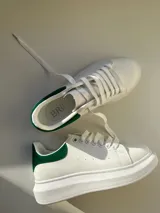 Championes blancos con detalles en verde en el talón y cordones blancos.