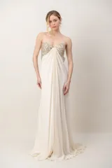 Vestido largo marfil de gasa, strapless, con bustier bordado en pedrería brillante y diseño drapeado en el frente.