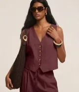 Chaleco femenino color bordó, confeccionado en viscolino, con escote en V, cierre frontal con botones contrastantes y bolsillos delanteros.