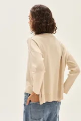 Sweater de tejido de punto color crudo, con escote redondo y mangas largas con puños acanalados. Presenta un calce cómodo y holgado.