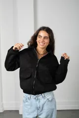 Campera corta de gamuza color marrón, con cierre frontal, cuello camisero y bolsillos frontales con solapa.