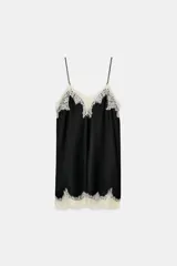 Top negro de tejido satinado con escote pico y tirantes finos. Presenta aplicación de encaje color crema en el escote y en el bajo, con un acabado en línea evasé.