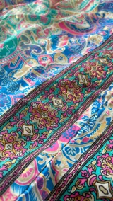 Vestido largo multicolor con estampado paisley en tonos azules, verdes y rosados, de corte holgado y escote halter.