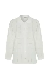 Camisa de punto calado color blanco, con cuello polo y cierre frontal de botones. Diseño de manga corta y patrón de cuadros sutiles.