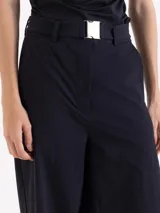 Pantalón de corte ancho y silueta relajada, confeccionado en tejido técnico con elasticidad. Presenta recortes verticales en el frente que terminan en aberturas en el ruedo y cuenta con un cinturón integrado con hebilla metálica de enganche.