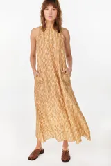 Vestido midi verde de lino italiano, con diseño sin mangas, cuello redondo y estampado de líneas onduladas punteadas. Cuenta con bolsillos laterales.