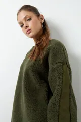 Buzo verde militar de tela tipo teddy, con cuello redondo y mangas largas con paneles de nylon.