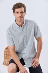 Camisa de manga corta confeccionada en mezcla de lino y algodón, con diseño de rayas verticales en tonos celeste y blanco. Cuenta con cuello camisero, botonadura frontal y bordado sutil en el pecho.