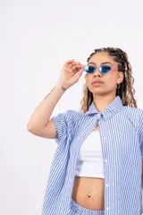 Conjunto de camisa y shorts a rayas verticales celestes y blancas. La camisa es de manga corta y se usa abierta sobre un top blanco.