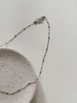 Gargantilla de cadena fina plateada en acero quirúrgico, decorada con pequeñas cuentas esmaltadas en colores variados distribuidas a lo largo de toda la pieza.