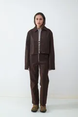 Campera corta de efecto cuero color marrón, con cuello solapa, cierre frontal y diseño de estructura ligera.