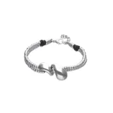Pulsera de aleación de metales bañados en plata, compuesta por dos tiras de cuentas metálicas y detalles de cuero marrón oscuro, con un adorno central de dos gotas plateadas.