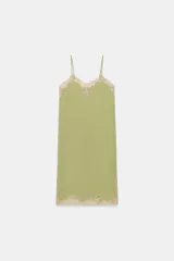 Vestido midi de satén color verde oliva, con escote recto y tirantes finos ajustables. Presenta detalles de encaje en color crema en el escote y en el bajo, con aberturas laterales.