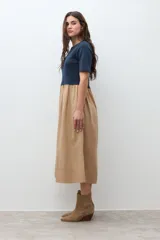 Vestido de dos piezas, con la parte superior tipo camiseta de manga corta y cuello redondo en color azul marino, y la parte inferior tipo falda midi de corte amplio y fruncido en color beige.