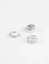 Set de tres earcuffs plateados de zinc. Incluye un earcuff grueso y liso, un earcuff más delgado y liso, y un earcuff doble con diseño de dos aros.