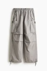 Pantalón cargo de algodón color gris claro, con corte holgado y cintura elástica ajustable con cordón. Presenta bolsillos cargo grandes en las piernas, pliegues cosidos en las rodillas y cordones ajustables en los bajos.