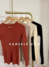 Remera de punto acanalado con escote redondo y cierre frontal parcial con botones. Presenta mangas largas y un ajuste entallado al cuerpo.