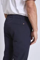 Pantalón de vestir azul marino, de corte recto, con bolsillos laterales y traseros. Se ajusta a la cintura con cinturón de cuero marrón.