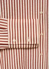 Camisa de corte recto y diseño a rayas verticales en tonos terracota y blanco, con cuello camisero, cierre frontal de botones y mangas largas con puños abotonados.