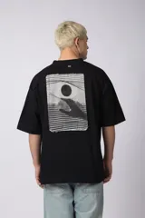 Remera de corte oversize confeccionada en algodón pesado, color negro. Presenta un bordado minimalista en el centro del pecho con forma de ojo y un parche estampado en la espalda que ilustra una mano abriendo una persiana.