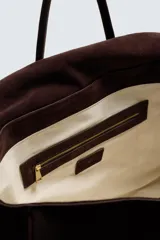 Bolso de mano marrón oscuro de cuero gamuzado, con cierre de solapa imantada y doble asa corta.