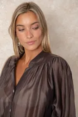 Camisa de organza blanca con cuello mao, diseño de manga larga tipo murciélago y cierre frontal con botones. Presenta un corte holgado y fluido.