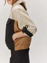 Chaquetas de lino bicolor en tonos blanco y beige, con diseño holgado, cuello alto, cierre frontal de botones, bolsillos con solapa en el pecho y mangas cortas con presilla y botón.