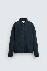 Cazadora regular fit color azul marino, confeccionada en tejido de lino con efecto ligeramente lavado. Presenta cuello solapa, manga larga con puño abotonado, bolsillos de vivo en la cadera y un bolsillo interior. Cierre frontal con cremallera.