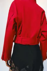Chaqueta corta roja ZARA Woman Collection con mezcla de algodón, cuello alto, manga larga, bolsillos delanteros y cinturón ajustable con lazada en el mismo tejido. Cuenta con cierre frontal con botones ocultos por solapa.