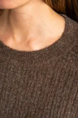 Sweater de punto texturado en color beige, con cuello redondo y mangas largas. Presenta un diseño de tejido acanalado vertical y corte holgado.