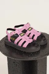 Sandalias de tiras anchas color crema con ajuste de hebilla al tobillo y suela track negra.