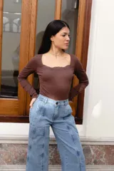 Body de manga larga color beige con escote cuadrado y detalles de puntilla en el escote y en las piernas.