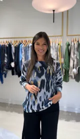 Sweater de punto con estampado animal print abstracto en tonos azules, negros y detalles en dorado. Presenta cuello redondo y mangas largas.