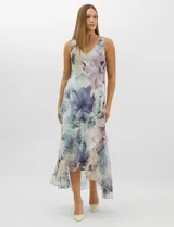 Conjunto compuesto por un vestido midi de gasa con estampado floral en tonos violeta, azul y crema, con escote en V, tirantes anchos y ruedo asimétrico con volados. Incluye una chaqueta corta tipo torera de mangas 3/4 confeccionada en la misma tela. Posee forro interno a tono.