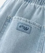 Bermuda de jeans de hombre, color negro con efecto desgastado o acid wash, de corte holgado. Posee cintura elástica con cordón de ajuste y bolsillos laterales.