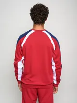 Buzo deportivo de manga larga, color principal rojo, con mangas azul marino y detalles en blanco que bajan desde el hombro hasta el puño. Presenta cuello redondo, logo Umbro y escudo del Club Nacional de Football en el pecho.