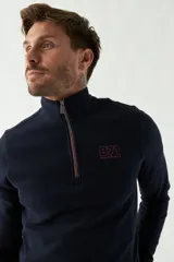 Buzo de felpa azul marino para hombre con medio cierre frontal, logo estampado en el pecho y puños. El modelo mide 1,80 m y usa talle M.
