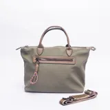 Cartera tipo bolso de mano color verde oliva, con detalles en cuero sintético color suela. Cuenta con cierre principal, bolsillo frontal con cierre y un llavero decorativo de cuerda trenzada multicolor. Incluye una correa larga ajustable y extraíble.