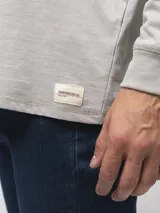 Remera de manga larga con cuello redondo, confeccionada en algodón, de corte clásico y diseño minimalista con detalle de etiqueta pequeña en el ruedo.