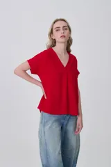 Blusa de poliéster color blanco con cuello en V, mangas cortas con dobladillo y corte holgado.