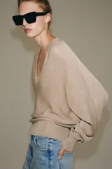 Jersey de punto metalizado color beige, con escote en V y manga larga.