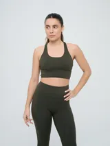 Top deportivo Umbro para mujer de color verde militar, con diseño de espalda cruzada y banda elástica inferior.