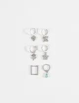 Set de tres pares de aros tipo argolla plateados con dijes colgantes variados: corazón con ojo turco, mariposa, trébol, flor, rectángulo y gota de cristal.