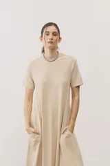 Vestido midi negro con diseño de manga corta, cuello redondo y bolsillos laterales, corte amplio y fluido.