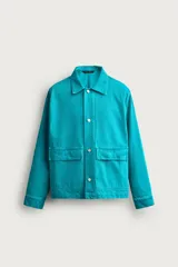 Cazadora relaxed fit de denim de algodón color turquesa, con cuello solapa, manga larga con puño abotonado, bolsillos frontales con solapa y cierre de botones metálicos.