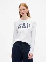 Remera de manga larga con cuello redondo, color blanco, con el logo de la marca estampado en el frente en color azul marino.