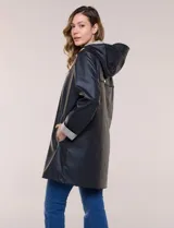 Pilot engomado impermeable color azul, de corte recto estilo trench con acabado resistente al agua. Cuenta con capucha integrada, cierre frontal con broches a presión, bolsillos laterales con ojal y forro interior de tela estampada a cuadros visible en la solapa y los puños.