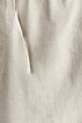 Short de lino liviano color beige, con cintura elástica y cordón oculto para ajustar. Presenta cierre decorativo, bolsillos laterales y un bolsillo trasero insertado. Corte estándar.