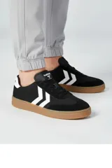 Championes urbanos Hummel modelo Yucatan, color negro con detalles en blanco y suela de goma color caramelo. Presentan el logo de la marca en la lengüeta y los icónicos chevrones laterales en contraste.