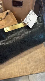 Sobre de cuero negro con textura craquelada y herraje metálico dorado en la solapa. Diseño elegante y sofisticado, ideal para eventos.